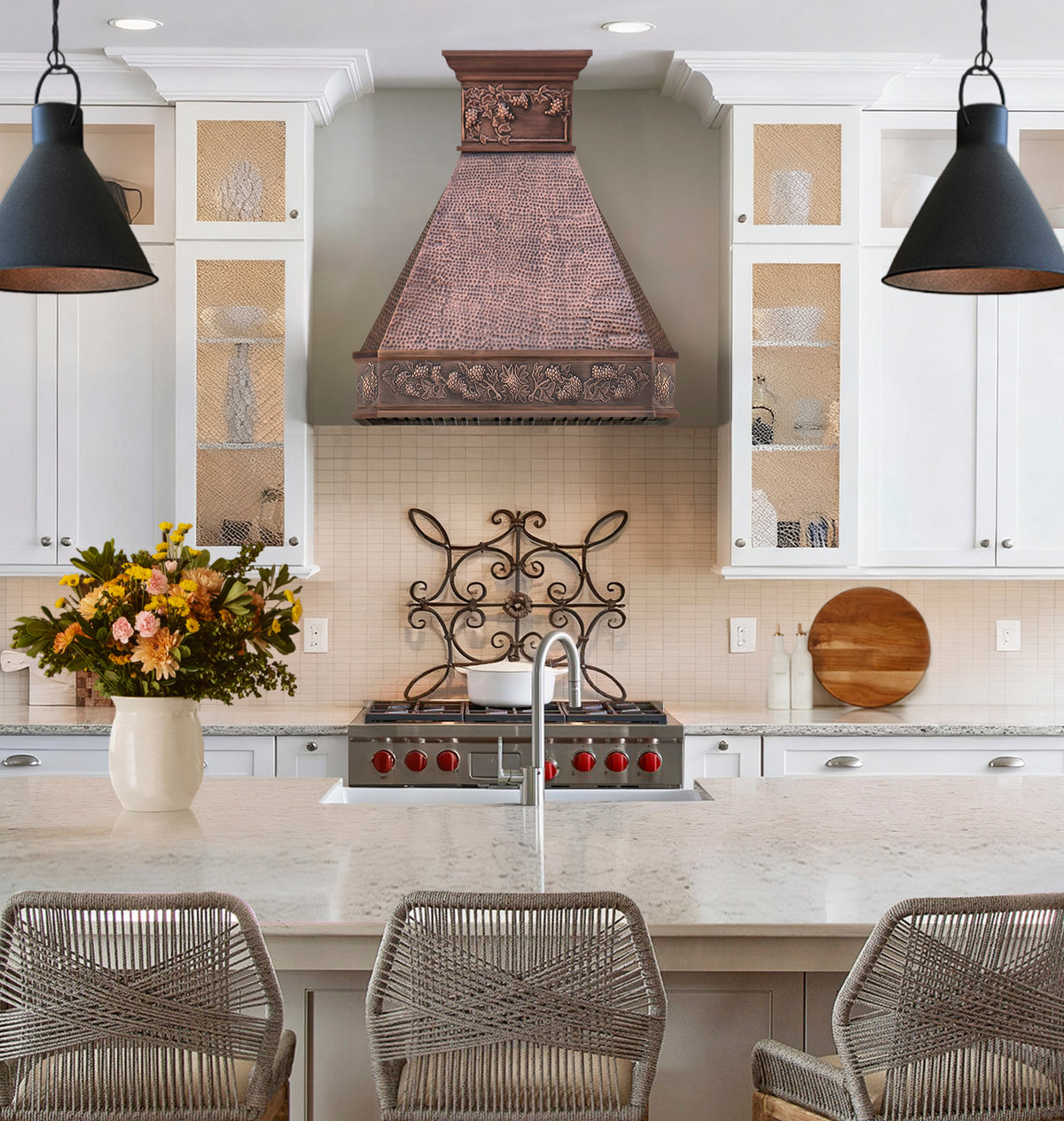 hammered antique copper range hood with grapevine relief detailing on the apron and upper trim in a modern kitchen