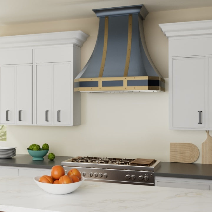 Modern kitchen with a decorative range hood, stove, and fruit on the counter.