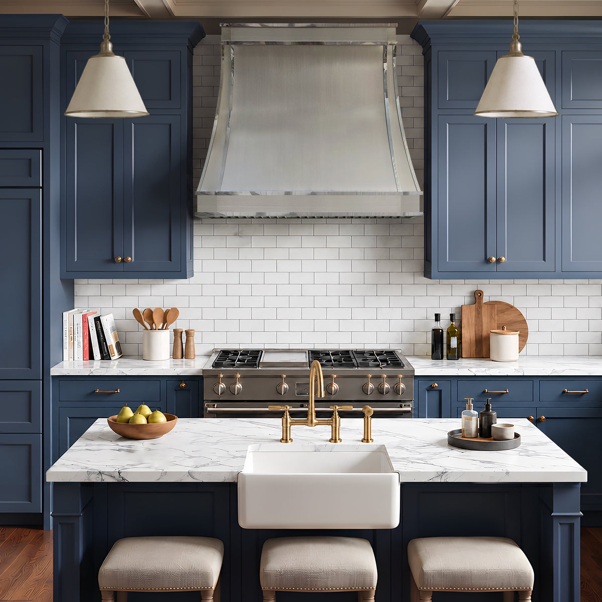 A modern stainless steel range hood in a luxury kitchen design featuring deep navy blue cabinets
