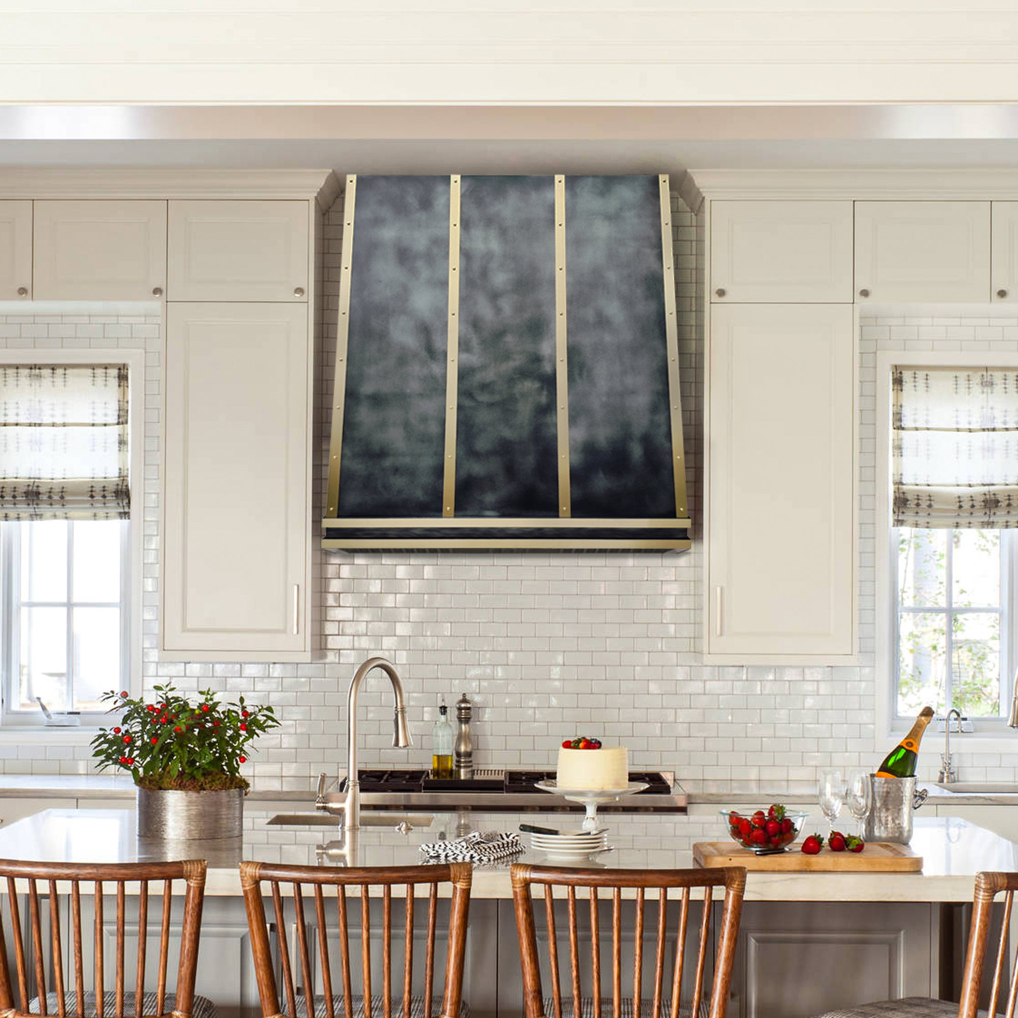 a zinc large range hood with a dark textured, smoky gray front and vertical gold trim, mounted in a bright, modern kitchen